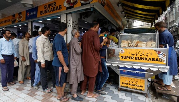 People wait for their turn to buy low-priced bun-kabab from a shop in Karachi, Pakistan June 10, 2022. — Reuters