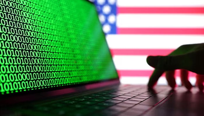 A hand is seen on a laptop with binary codes displayed in front of the USA flag in this illustration taken, August 19, 2022. — Reuters