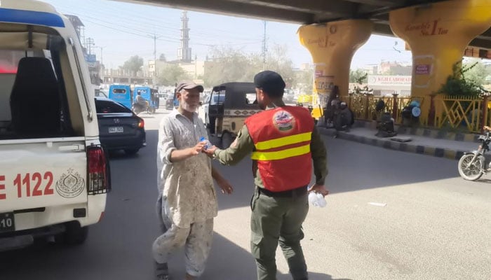 In this image, a Rescue 1122 personnel providing water to a citizen during a heatwave in Karachi on May 2, 2026. — Facebook@Commissioner Karachi Office