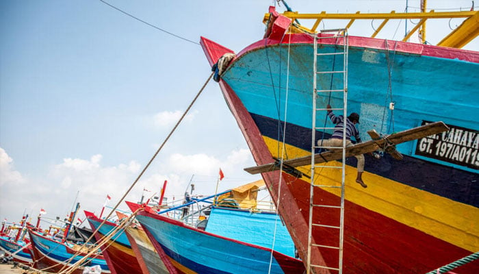 A worker is painting the fishing boat. —AFP/File