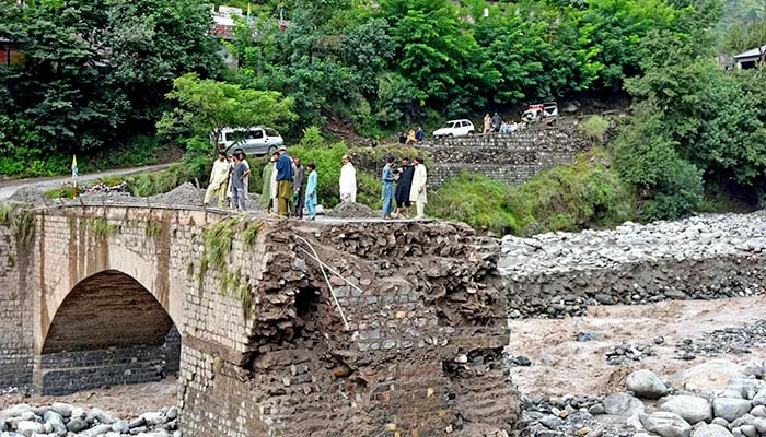 nlookers gather near a destroyed bridge after flash floods on the outskirts of Muzaffarabad, the capital AJK, on August 15, 2025. — AFP