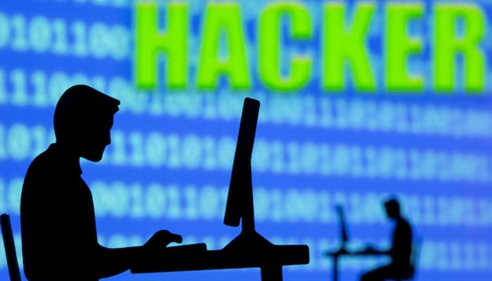 A 3D printed model of men working on computers are seen in front of displayed binary code and words Hacker in this illustration taken, July 5, 2021.—Reuters