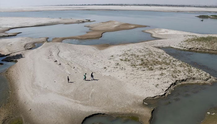 People walk on the dry patch of the Indus River, in Jamshoro, Pakistan, March 15, 2025.—Reuters