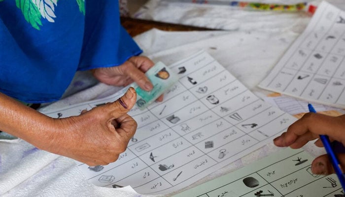 A voter with an ink mark on the thumb goes through paperwork to cast a vote during the general election in Karachi, Pakistan, on February 8, 2024. — Reuters