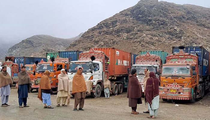 People stand next to parked trucks loaded with supplies at the Torkham border crossing following the closure of the border crossing between Pakistan and Afghanistan on March 3, 2025. — Reuters
