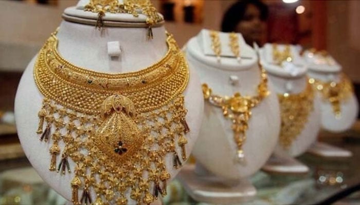 A saleswoman stands behind the showcased gold necklaces at a jewellery showroom in Agartala, capital of Indias northeastern state of Tripura.—Reuters/File