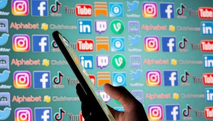 The representational image shows a person holding smartphone in front of displayed social media logos in this illustration taken, May 25, 2021. — Reuters