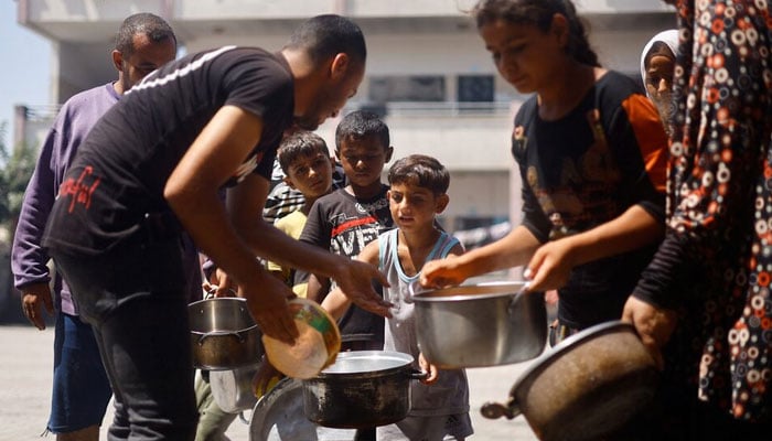 Palestinians gather to receive food cooked by a charity kitchen, amid food scarcity, as Israel-Hamas conflict continues, in Khan Younis in the southern Gaza Strip, June 26, 2024. — Reuters
