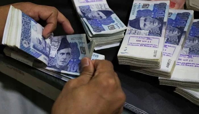 An employee counts Pakistani rupee notes at a bank on August 22, 2023. — Reuters