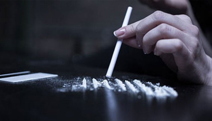 The representational  image depicts a person using a rolled-up tube to snort lines of a white, powdery substance. — UKOT website/File