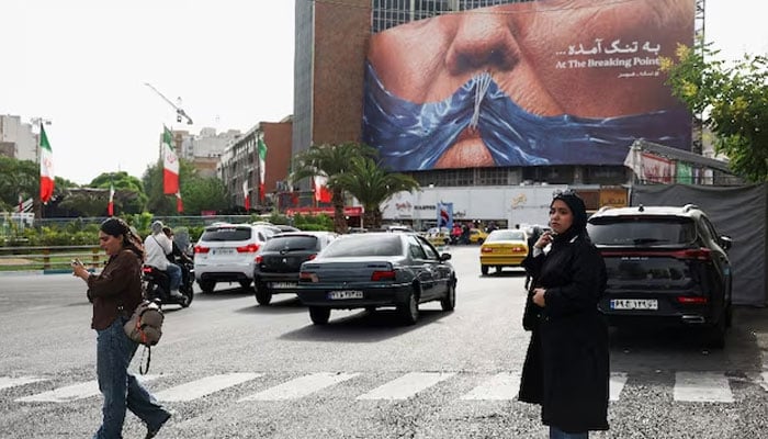 A woman walks past an anti-US billboard depicting U.S. President Donald Trump and the Strait of Hormuz, in Tehran, Iran, May 17, 2026.—Reuters