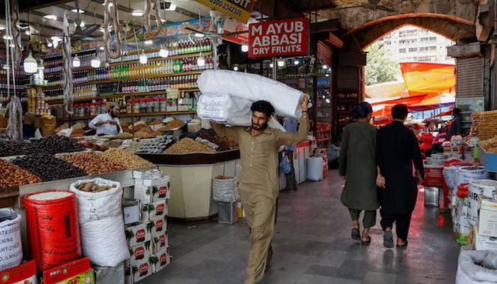 A man walks with sacks of supplies on his shoulder to deliver to a nearby shop at a market in Karachi, Pakistan June 11, 2024.—Reuters