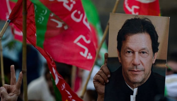An activist of the opposition party Pakistan Tehreek-e-Insaf (PTI) holds a portrait of PTI founder Imran Khan during an anti-government rally on October 28, 2022. — AFP