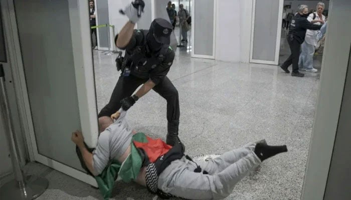 A Member of the Ertzaintza detain an activist at Bilbao airport. —AFP