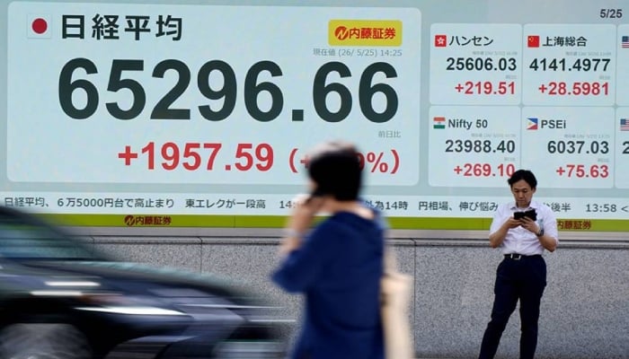 An electronic quotation board (L) displays the Nikkei Stock Average on the Tokyo Stock Exchange along a street in Tokyo on May 25, 2026. — AFP