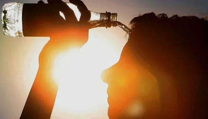 A man cools himself by pouring water on his face under the scorching sun. — AFP/File