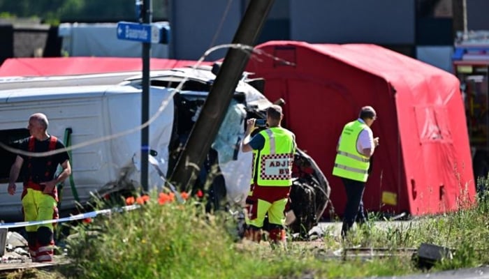 Staff cover a hearse parked next to the crashed bus at the site of an accident after a train crashed into a school bus, at the railway crossing Vierhuizen in Buggenhout, some 20kms north of Brussels on May 26, 2026.— AFP