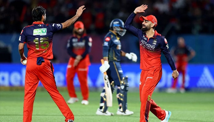 Royal Challengers Bengalurus  Bhuvneshwar Kumar celebrates with Virat Kohli after taking the wicket of Gujarat Titans Rahul Tewatia.— Reuters/File