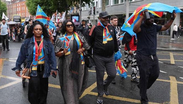 Dublin-based producer and musician Chris Kabs (R) walks with a Congolese flag, down O’Connell Street in central Dublin at the head of a protest to demand justice following the death of Congolese citizen Yves Sakila, after he was violently restrained by shop security guards who suspected him of shoplifting, on May 30, 2026. —AFP