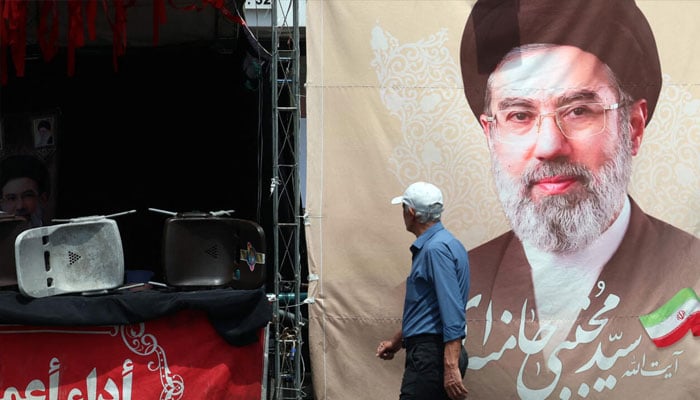 An Iranian man walks past a billboard carrying a picture of Irans supreme leader Mojtaba Khamenei erected along a street in Tehran on May 28, 2026.—AFP