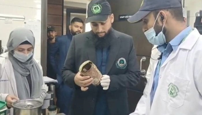This image shows officials of the food authority inspecting standard and substandard food items. — APP/File