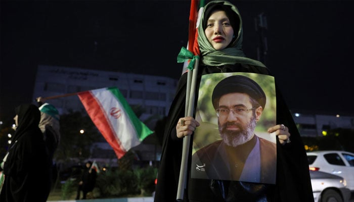 A woman holding a portrait of Irans Supreme Leader Ayatullah Mojtaba Khamenei. —AFP/File