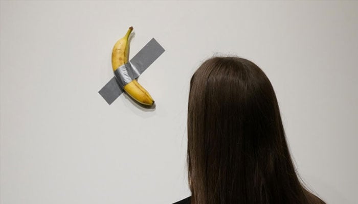 A woman looking at Italian visual artist Maurizio Cattelans conceptual work Comedian. — AFP/File