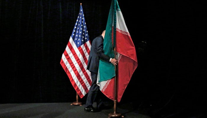 A staff member removes the Iranian flag from the stage after a group picture with foreign ministers and representatives during the Iran nuclear talks in Vienna on 14 July 2015. — AFP/File