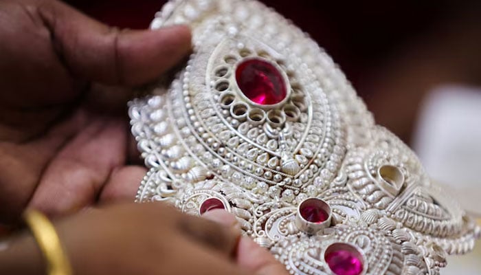 A goldsmith inserts a stone inside a silver crown at a jewellery making workshop in Mumbai, India, August 14, 2025.—Reuters