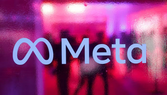 People walk behind a logo of Meta Platforms company, during a conference in Mumbai, India, September 20, 2023.—Reuters