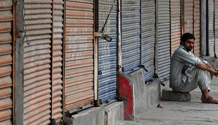 A man sits near a closed market, during a shutter down and wheel-jam strike. — Reuters/File