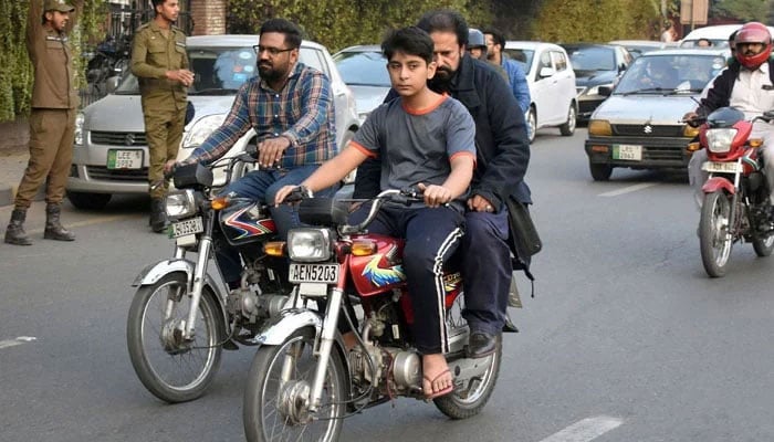A young boy is riding a motorcycle in Lahore in November 19, 2023. — Online