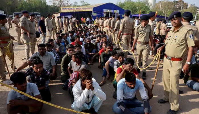 Police officers stand next to men they believe to be undocumented Bangladeshi nationals after they were detained during raids in Ahmedabad, India on April 26, 2025. — Reuters