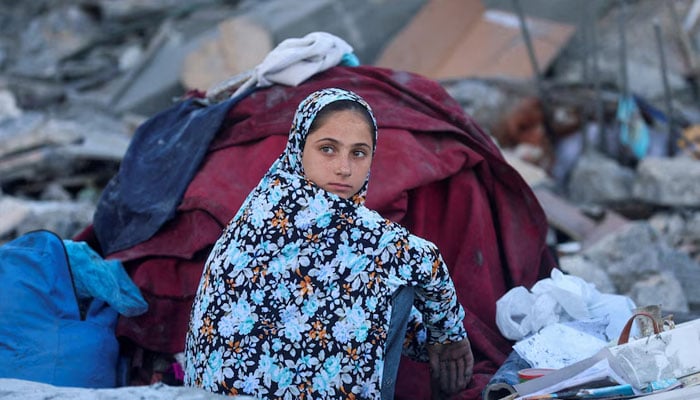 A Palestinian girl sits beside a destroyed building. —Reuters/File