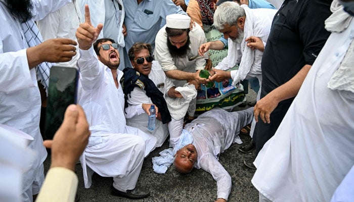 A demonstrator collapses as government employees protest against inflation, demanding better wages, outside the Parliament House before the start of the budget session in Islamabad on June 12, 2026. — AFP