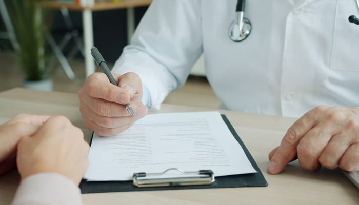 Medic in uniform is ticking symptoms in patients medical records in this representational image. — Unsplash