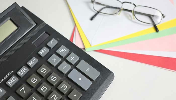 Representational image shows a calculator and glasses on colourful papers. — Unsplash/File