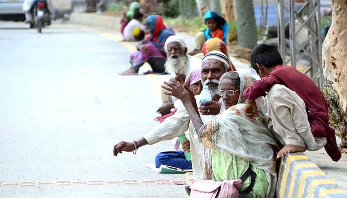 A representational image showing people sitting on the roadside in Qasimabad on July 17, 2021. — APP