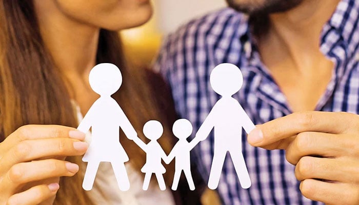 This representational image shows a white paper cutout representing a family of four being held by two people. — Instagram@ibicuy_noticias/File