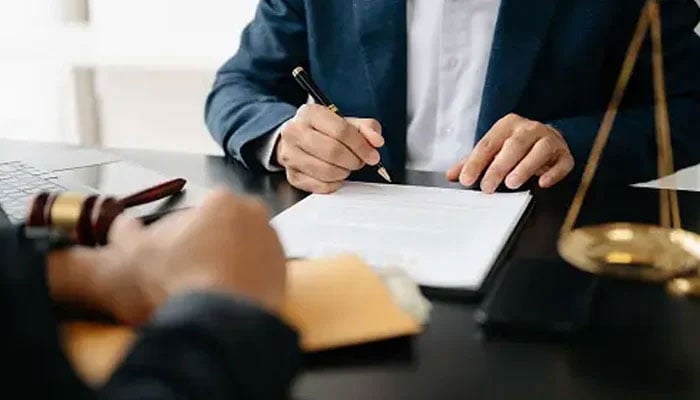 In this representational image, a lawyer is writing on a paper at his chamber. — Unsplash/File