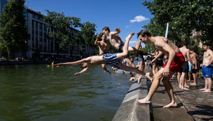 Young people dived into the Canal Saint-Martin in Paris to beat the heat. —AFP/File