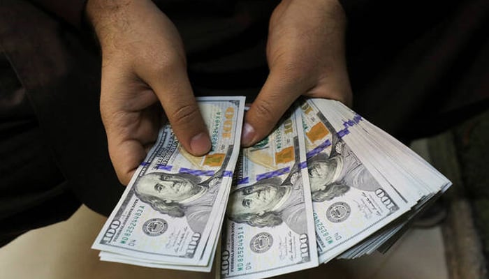 A trader counts US dollar banknotes at a currency exchange booth in Peshawar, January 25, 2023. — Reuters