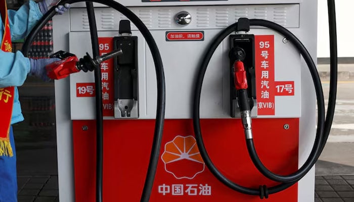 An attendant holds a petrol nozzle after refuelling a car at a PetroChina gas station in Beijing, China, March 10, 2026.—Reuters