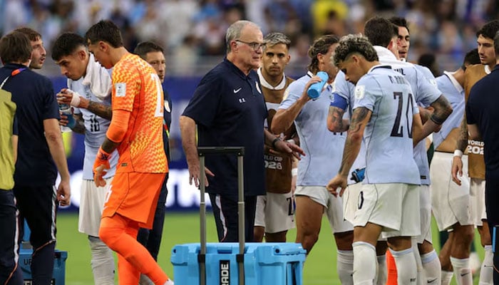 Uruguay coach Marcelo Bielsa gives instructions to Maxi Araujo and teammates during a hydration break. —Reuters