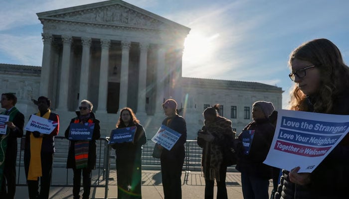 A small group led by members of the clergy gather for a vigil prior to arguments in Noem v. Al Otro Lado, a case to determine if noncitizens blocked on the Mexican side of the border by U.S. officials can apply for asylum, at the US Supreme Court building in Washington, D.C., US, March 24, 2026. — Reuters