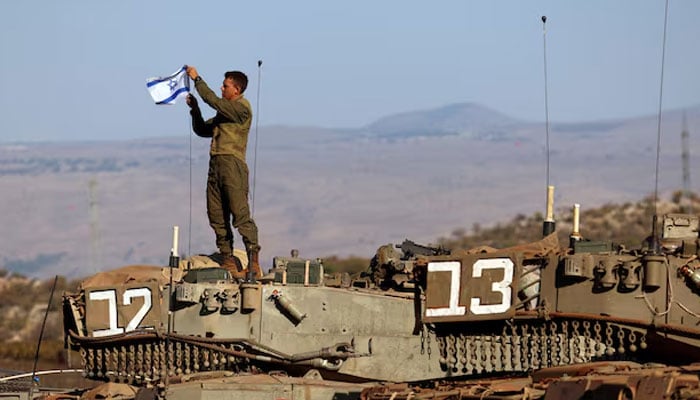 A soldier installs an Israeli flag on a tank during a military drill near Israels border with Lebanon in northern Israel, October 26, 2023. — Reuters