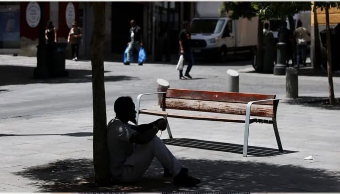 A man sits in the shade of a tree to escape the heat during a heatwave in Madrid, Spain, June 23, 2026. — Reuters
