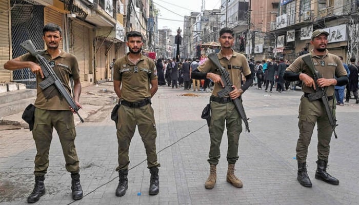 Policemen stand guard during Ashura procession in Lahore on July 4, 2025. — AFP
