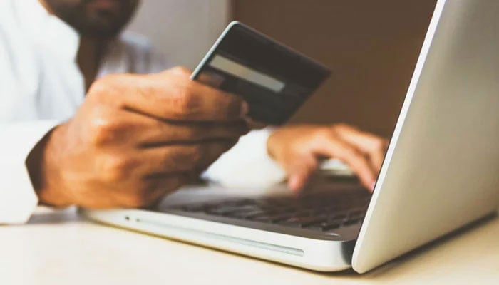 The representational image shows a man holding a credit card to pay online. — Unsplash/File