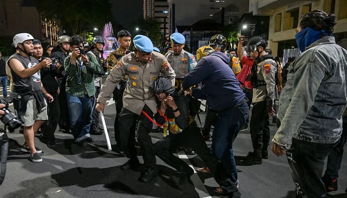 Indonesian police officers arrest a student following clashes during a protest in Surabaya. —AFP/File